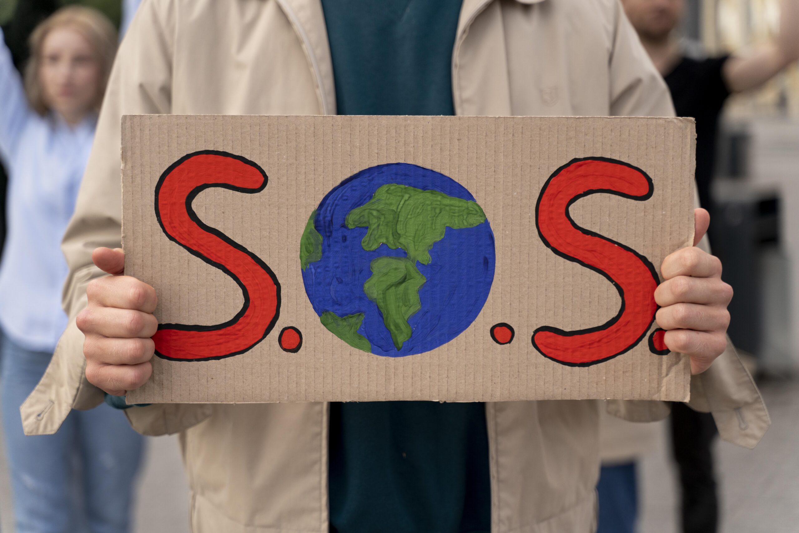 mujer protestando contra el cambio climático lleva un cartel que dice SOS